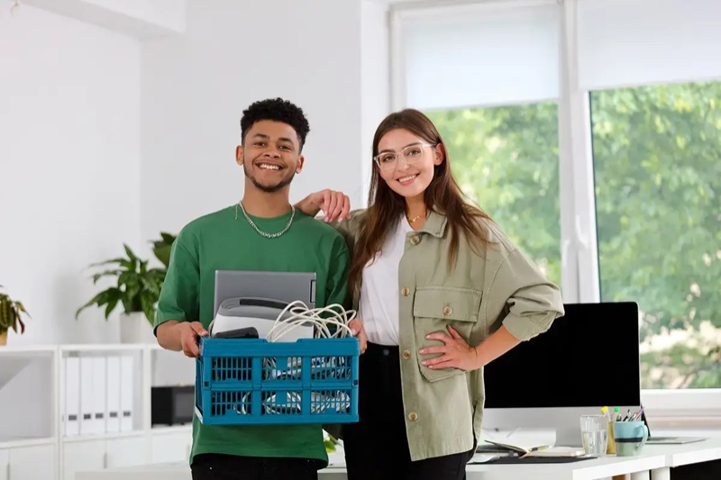 Two staff members holding a crate of collected electronic waste and cables